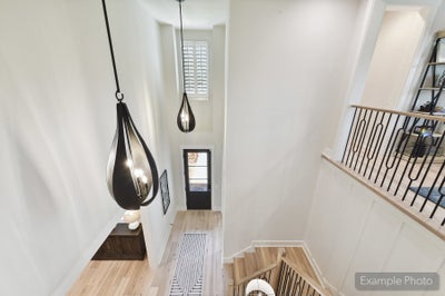 Two-story foyer with two black teardrop pendant lights, wood staircase with iron balusters, and light hardwood floors