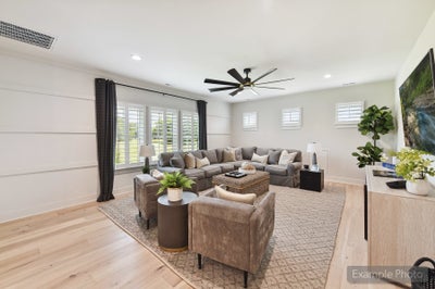 Spacious living room with gray sectional sofa, hardwood floors, ceiling fan, and shiplap accent wall