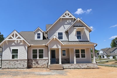 Two-story craftsman home with gray shingle siding, stone foundation, and covered front porch