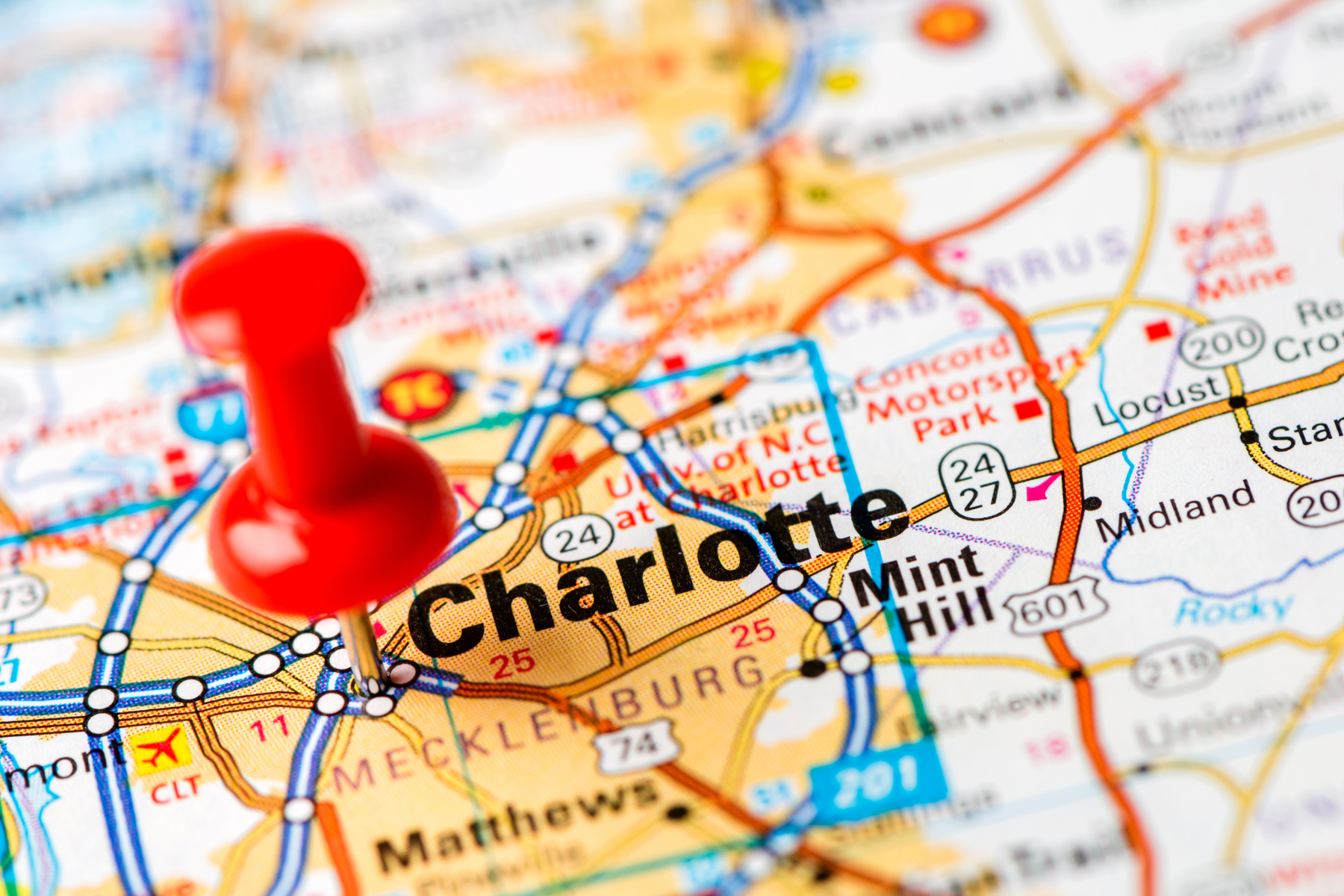 Red pushpin marking Charlotte, North Carolina on a road map showing surrounding cities and highways