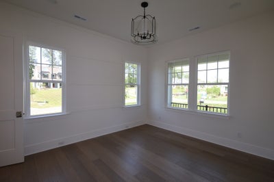 Empty room with white shiplap walls, dark hardwood floors, and a black pendant light fixture