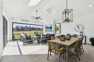 Covered outdoor patio with dining table, seating area, vaulted ceiling, and open views of a grassy yard