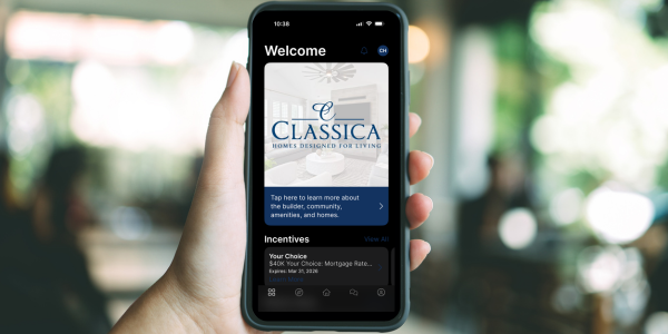 Hand holding a smartphone displaying the Classica Homes mobile app welcome screen with incentives section visible.