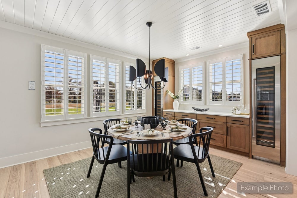 Dining area with round table, black chairs, shiplap ceiling, plantation shutters, and built-in wine cooler with wood cabinetry