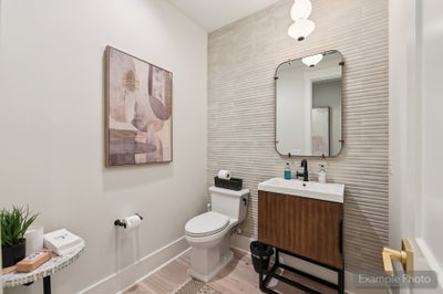 Powder room with textured accent wall, wood vanity, framed mirror, and modern pendant light