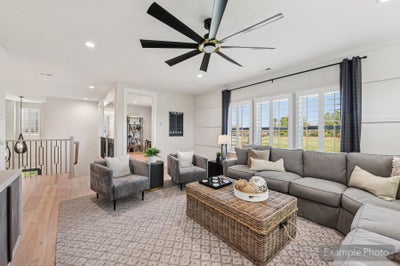 Living room with gray sectional sofa, wicker coffee table, large ceiling fan, and hardwood floors