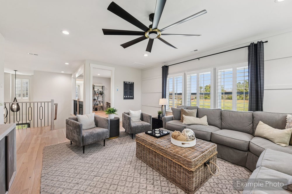 Living room with gray sectional sofa, wicker coffee table, large ceiling fan, and hardwood floors