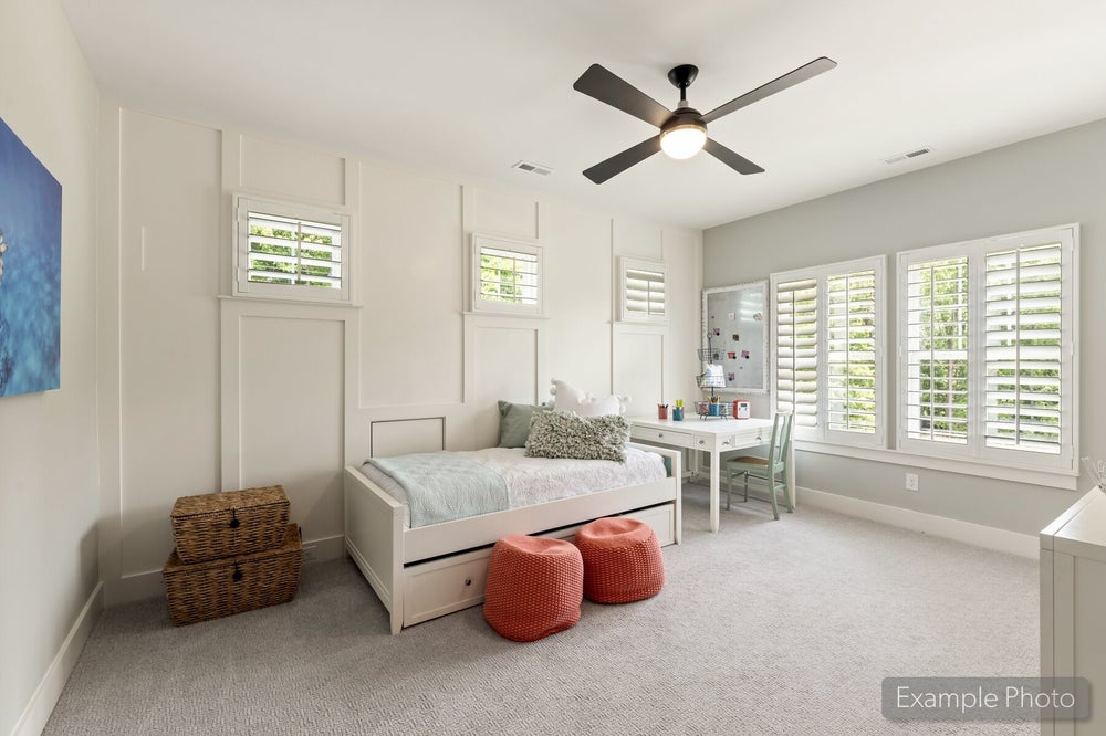Child's bedroom with white daybed, built-in wall paneling, ceiling fan, and plantation shutters on multiple windows