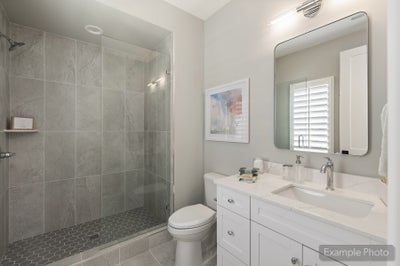 Bathroom with glass walk-in shower, gray tile walls, white vanity, and quartz countertop