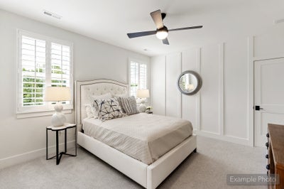 Bedroom with tufted upholstered bed, ceiling fan, plantation shutters, and white board-and-batten accent wall