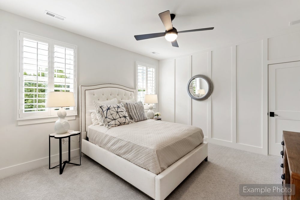 Bedroom with tufted upholstered bed, ceiling fan, plantation shutters, and white board-and-batten accent wall