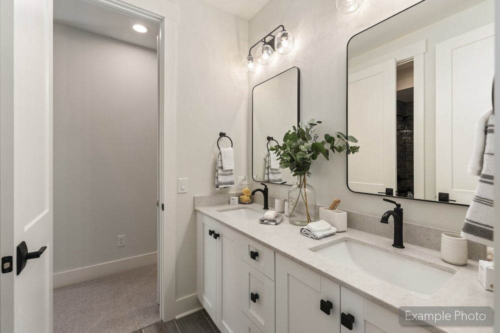 Bathroom with double vanity, white cabinets, stone countertops, and black fixtures with two mirrors above