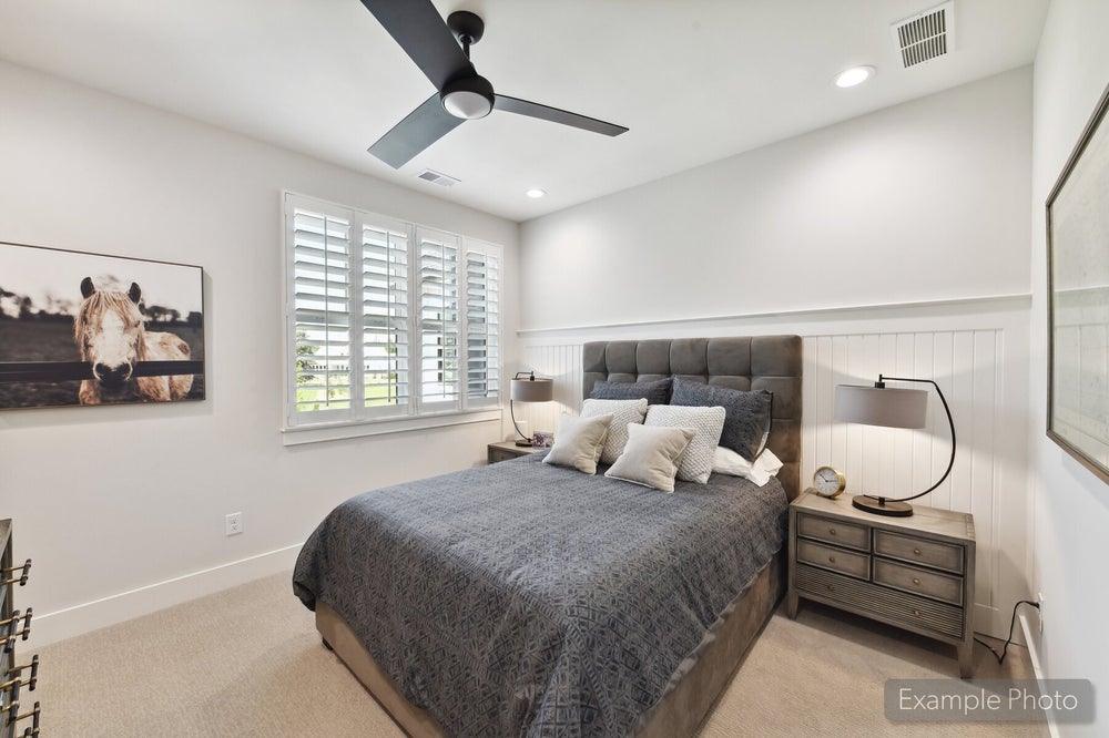 Bedroom with tufted headboard, shiplap accent wall, ceiling fan, and plantation shutters on window