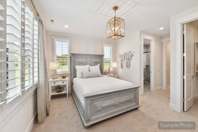 Bedroom with gray wood bed frame, gold pendant light, plantation shutters, and ensuite bathroom access