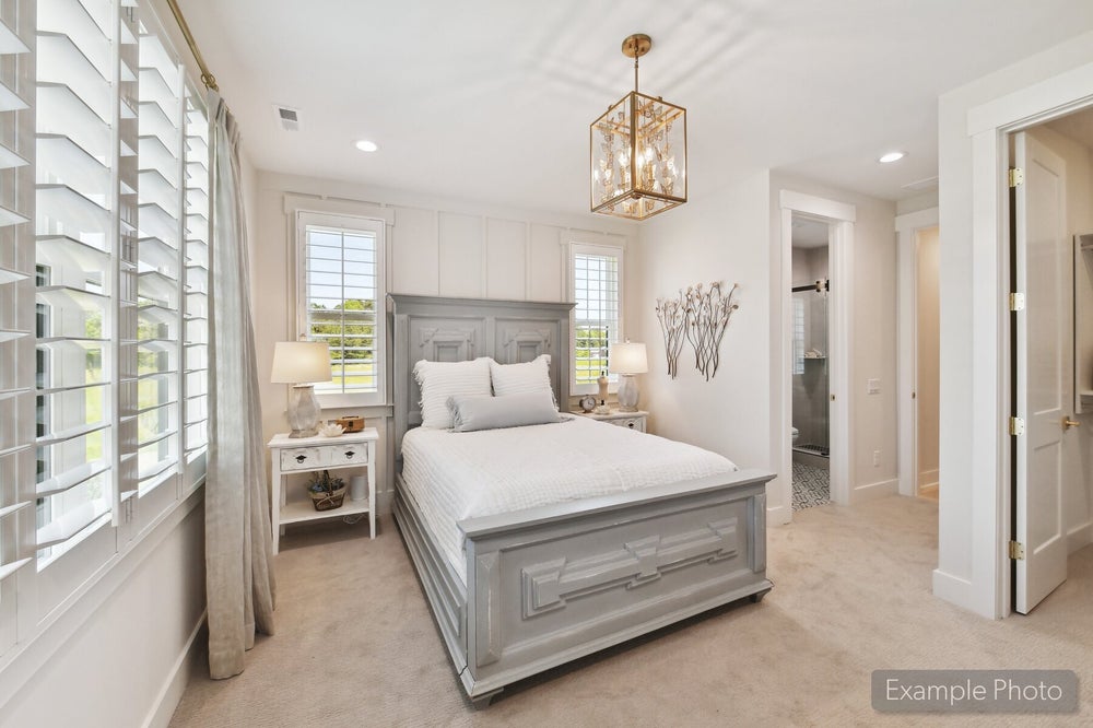 Bedroom with gray wood bed frame, gold pendant light, plantation shutters, and ensuite bathroom access