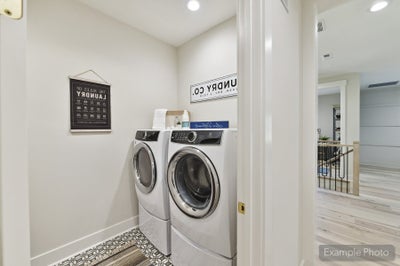 Laundry room with front-load washer and dryer on pedestals and decorative tile floor