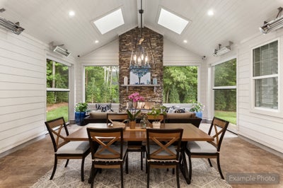 Sunroom dining area with vaulted shiplap ceiling, skylights, stone fireplace, and wood dining table for six