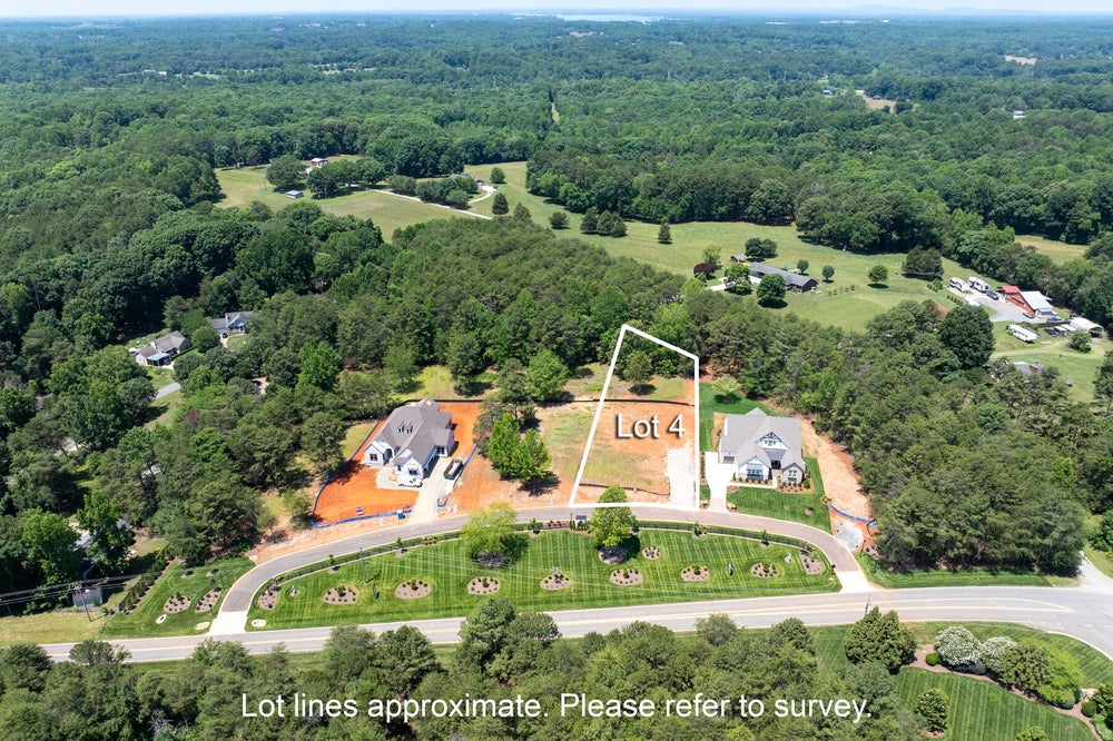 Aerial view of Lot 4 vacant residential lot between two new homes in a wooded suburban neighborhood
