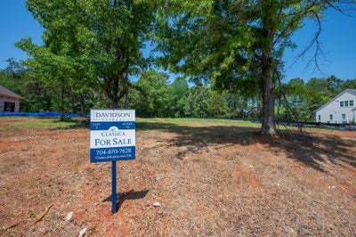 Vacant residential lot for sale at Davidson Retreat, 0.96 acres with mature trees and neighboring homes visible.