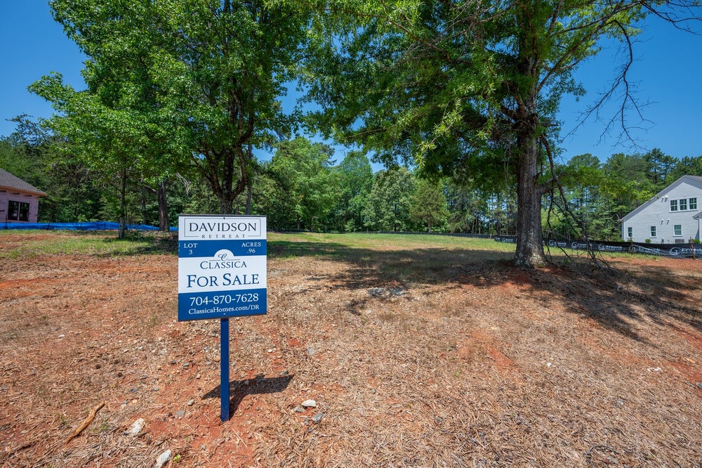 Vacant residential lot for sale at Davidson Retreat, 0.96 acres with mature trees and neighboring homes visible.