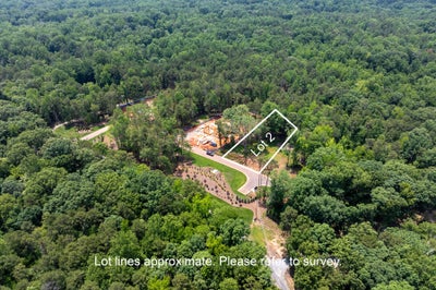 Aerial view of Lot 2, a wooded residential building lot with active construction and a curved driveway surrounded by trees.