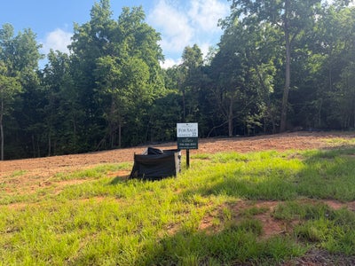 Vacant homesite 22 for sale with cleared graded land and wooded tree line in background
