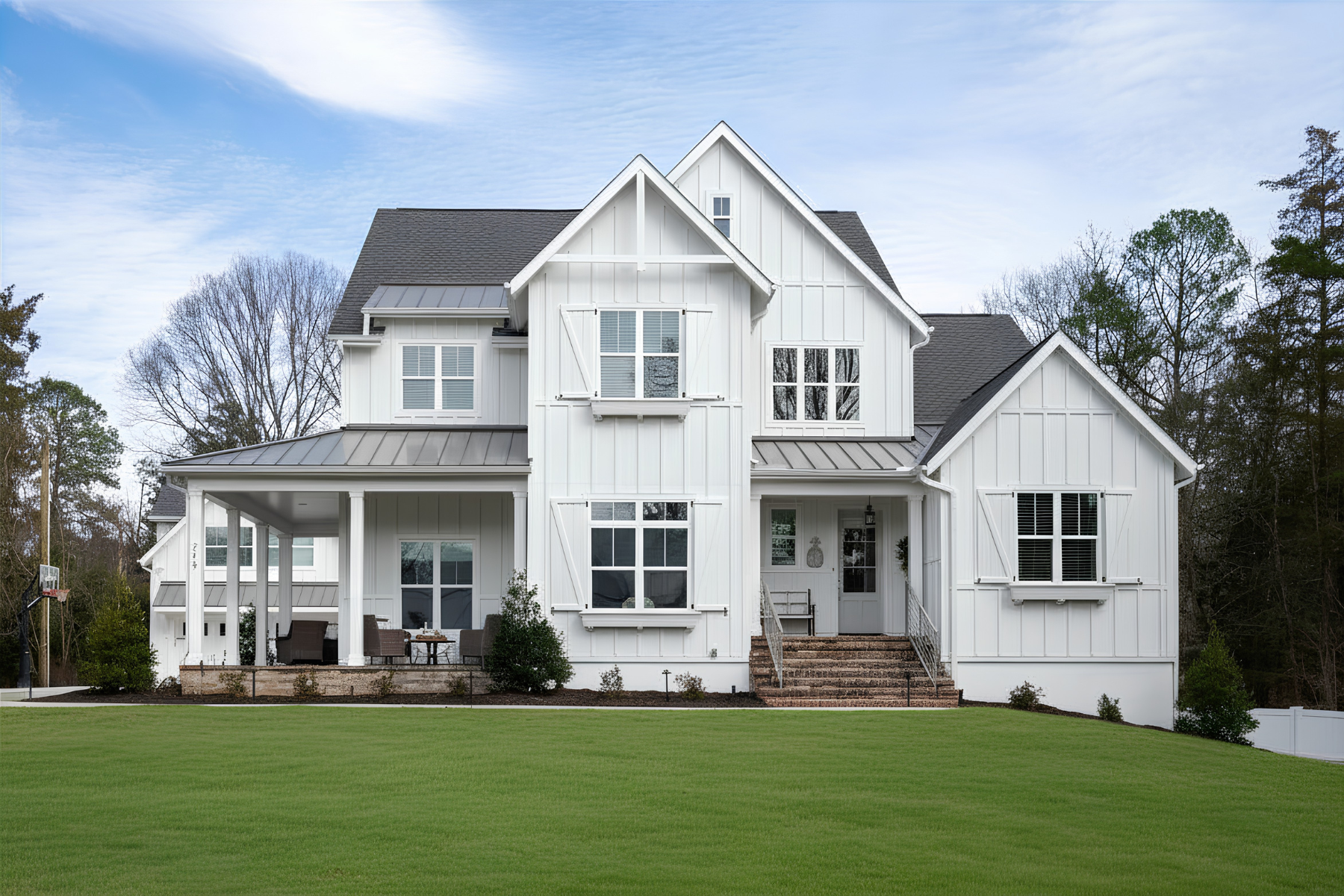 Two-story white farmhouse with board-and-batten siding, metal roof, covered porch, and green lawn