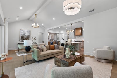 Open-concept living room with vaulted ceiling, hardwood floors, and view into kitchen