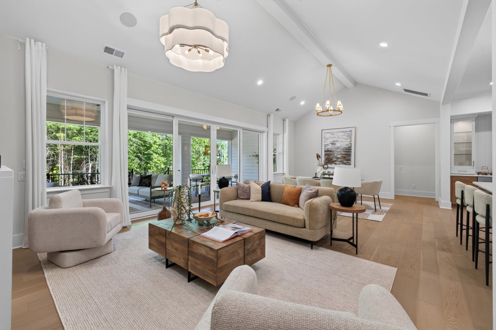 Open living room with vaulted ceiling, hardwood floors, and sliding glass doors to outdoor patio