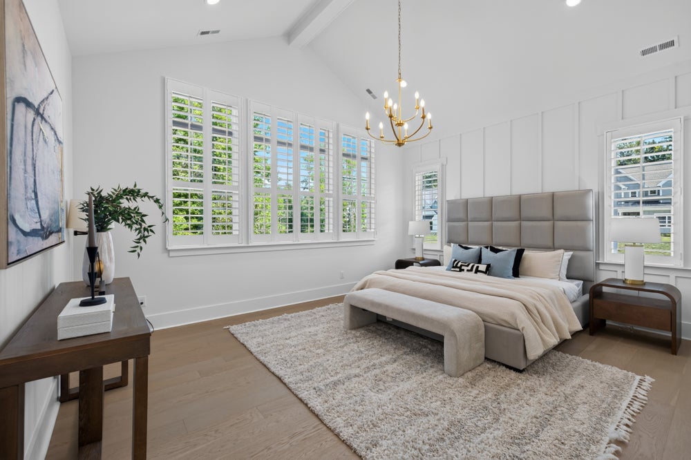 Master bedroom with vaulted ceiling, chandelier, plantation shutters, and hardwood floors