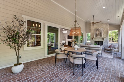 Covered patio with brick floor, round dining table, seating area, and stone fireplace