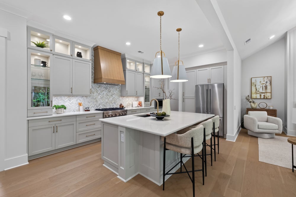 Kitchen with gray cabinets, center island with bar seating, wood range hood, and herringbone tile backsplash