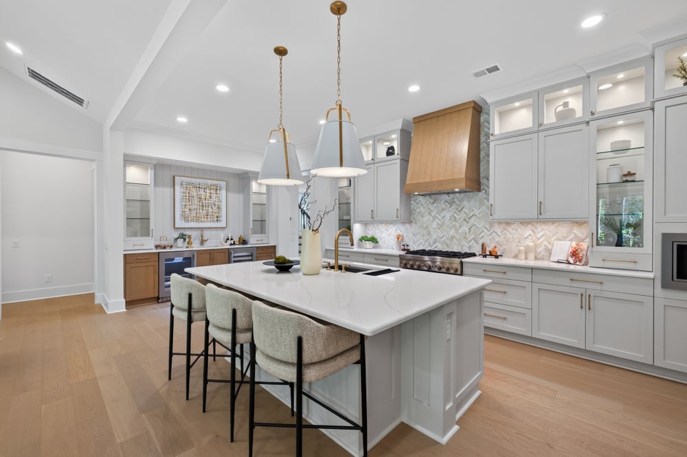 Large kitchen with white cabinets, center island with seating, herringbone tile backsplash, and hardwood floors