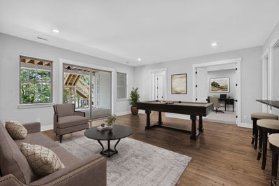 Game room with pool table, seating area, bar stools, and hardwood floors with patio door access