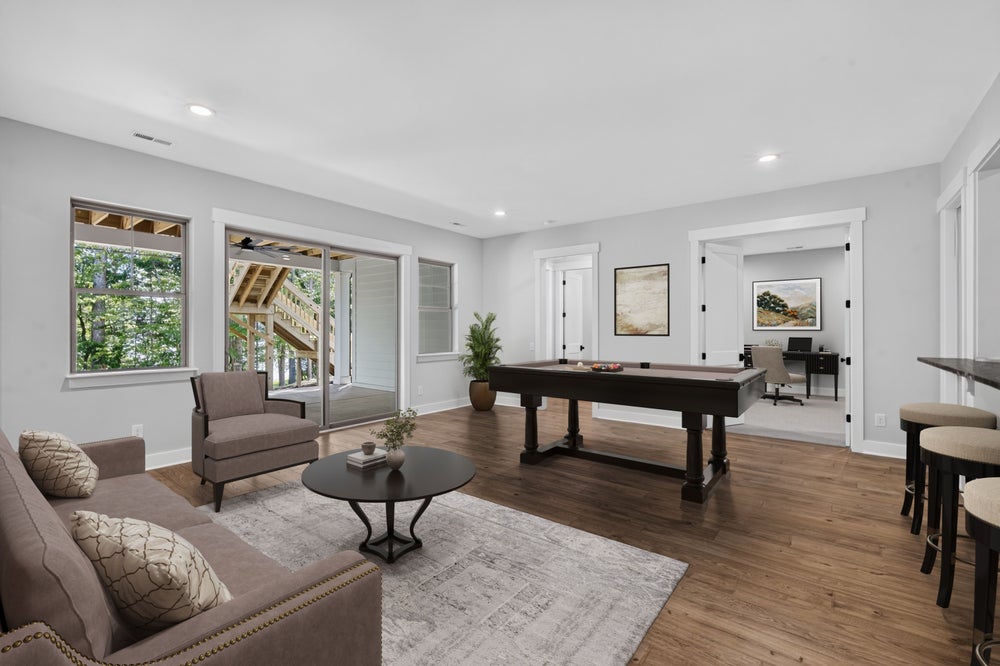 Game room with pool table, seating area, bar stools, and hardwood floors with patio door access