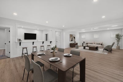 Open-concept living space with dining table, bar counter with stools, and sitting area on light hardwood floors