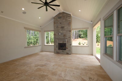 Sunroom with floor-to-ceiling stone fireplace, vaulted ceiling, ceiling fan, and tile floors