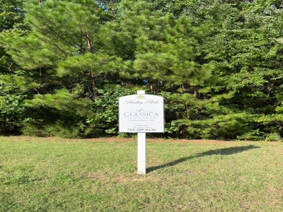Classica Homes subdivision sign for Hadley Park community on a grassy lot surrounded by pine trees