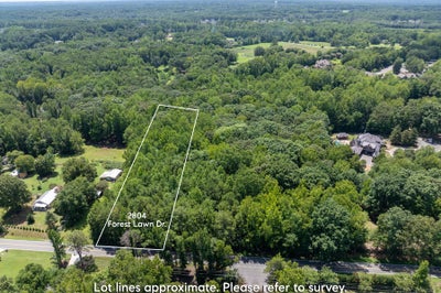 Aerial view of wooded vacant lot at 2804 Forest Lawn Dr with marked boundaries, surrounded by trees and nearby homes