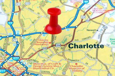 Red pushpin marking Charlotte, North Carolina on a road map showing highways and local landmarks