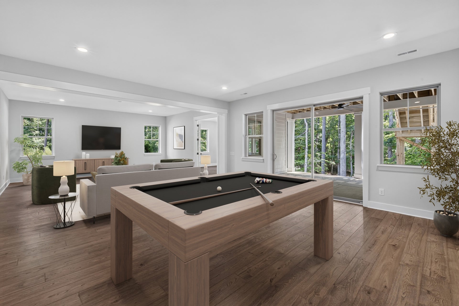 Game room with pool table, hardwood floors, and open living area with wall-mounted TV