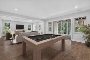 Game room with pool table, hardwood floors, and open living area with wall-mounted TV