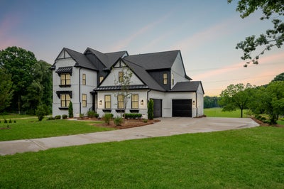 Two-story modern farmhouse with white board-and-batten siding, black roof, two-car garage, and large front lawn