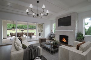 Living room with stone fireplace, wall-mounted TV, and sliding doors opening to a patio with outdoor dining area.