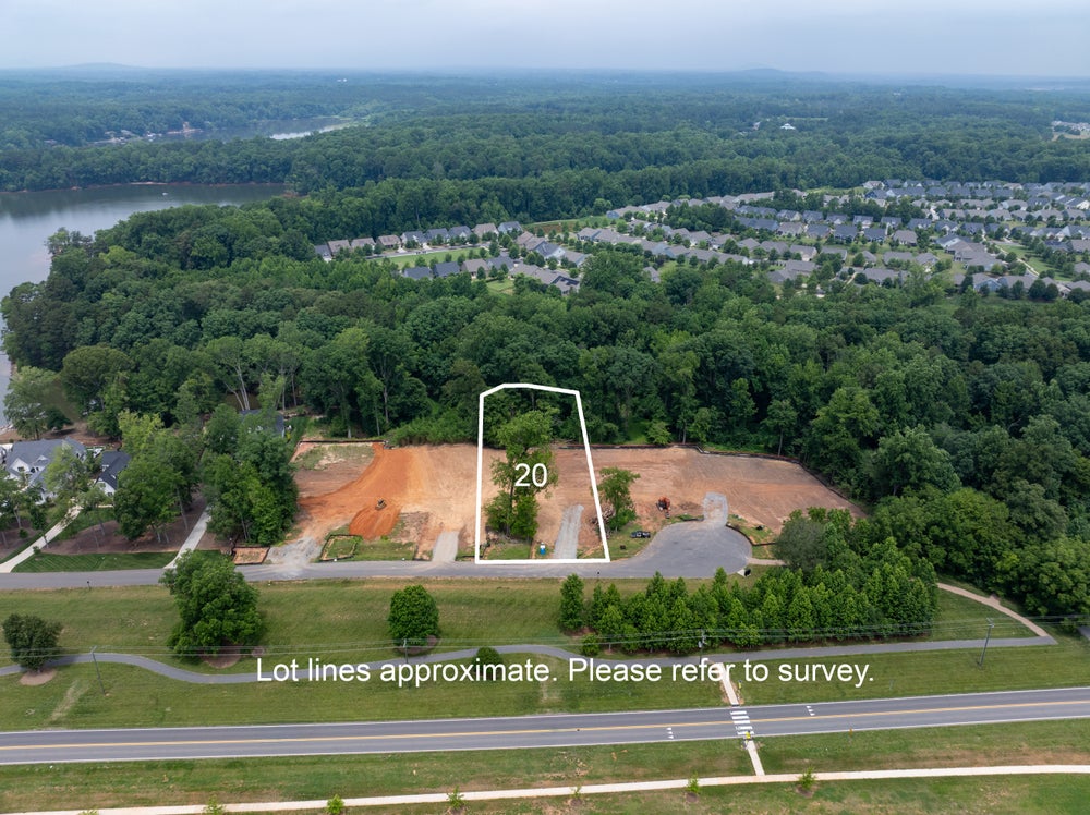 Aerial view of lot 20, a cleared residential building lot near a lake and wooded neighborhood