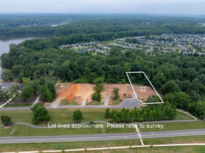 Aerial view of lot 22, a cleared residential building lot near a lake and wooded neighborhood