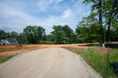 Gravel road through a cleared residential construction site with red clay soil and trees nearby
