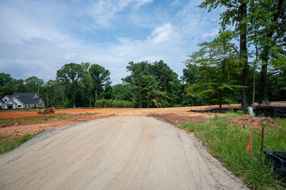 Gravel road through a cleared residential construction site with red clay soil and trees nearby