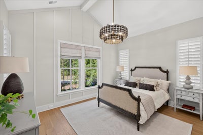 Bedroom with vaulted ceiling, dark wood bed frame, chandelier, and hardwood floors