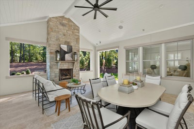 Covered patio with stone fireplace, vaulted ceiling, ceiling fan, and outdoor dining and seating areas